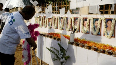 A member of the French aid group Action Contre La Faim places a wreath in front of the photographs of his 17 slain colleagues at their memorial in Batticaloa, Sri Lanka on August 11, 2006.