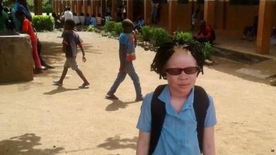 Josina usando seus novos óculos apropriados fora da sala de aula no distrito de Chiuta, na província de Tete, em Moçambique. Desde obter os óculos, Josina tem apresentado um melhor desempenho acadêmico, embora as escolas estão fechadas por causa da pandemia do Covid-19 no momento.