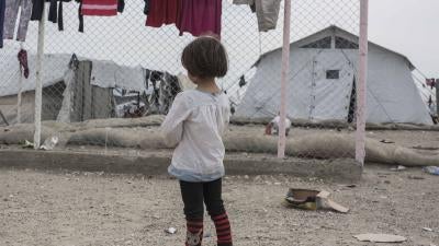A girl stands in front of a chainlink fence