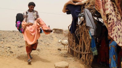 A woman is carried by her brother outside a home in Malus, Yemen. 