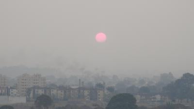 The sun rises over a city skyline covered in smoke