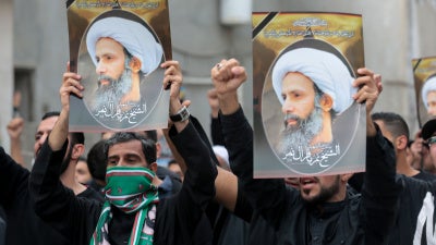 Men hold placards bearing portraits of a prominent Shia Muslim cleric, Nimr al-Nimr, whose execution sparked demonstrations in 2016 by the country's minority Shia citizens against systematic governmental discrimination. Some of the alleged child offenders currently on trial were accused of attending similar protests. 