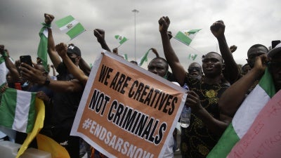 People hold banners and flags as they protest against police brutality in Lagos, Nigeria, Monday Oct. 19, 2020. 