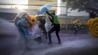 Democracy demonstrators take cover with inflatable ducks and umbrellas as police use water cannons during a protest rally near the parliament in Bangkok, November 17, 2020. © 2020 AP Photo/Wason Wanichakorn