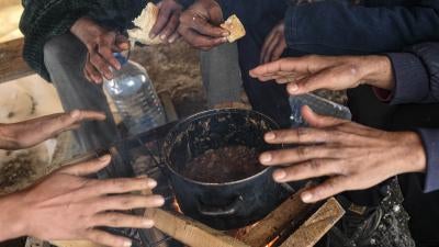 Migrants warm their hands above a fire at the Lipa camp, outside Bihac, Bosnia and Herzegovina, Monday, January 11, 2021. The camp was closed on December 23, 2020 and destroyed in a fire the same day. 