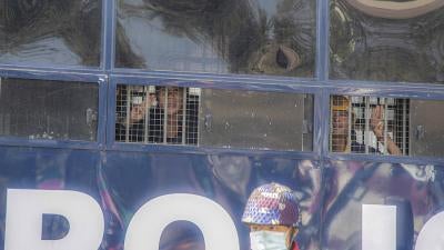 Protesters raise three-finger salutes from inside a police vehicle after a being detained during an anti-coup protest in Mandalay, Myanmar, February 9, 2021.