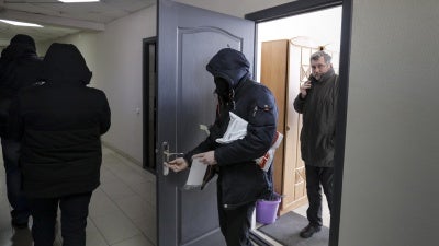 Police in Minsk carry documents and computers out of the office of the Belarusian Association of Journalists on February 16, 2021, as Andrei Bastunets, the head of the organization, looks on.