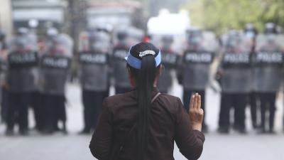 A protester flashes the three-fingered salute in front of police in Mandalay, Myanmar, February 20, 2021.