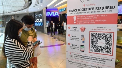Cinemagoers downloading the TraceTogether app on their mobile phones to check in before entering Shaw Theatres at JCube mall in Singapore, October 31, 2020.