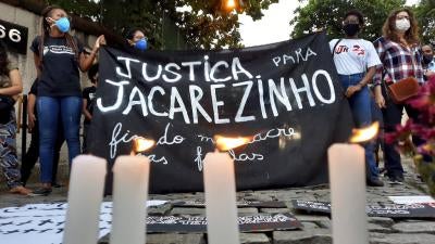 Activists hold a sign that reads in Portuguese "Justice for Jacarezinho. End massacres in favelas" during a protest a day after police killed 27 people during an operation in Jacarezinho favela, in Rio de Janeiro, Brazil, on May 7, 2021. 