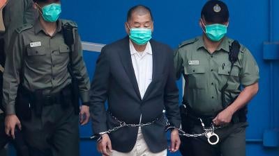 In this December. 12, 2020, file photo, Jimmy Lai,  center, who founded the pro-democracy newspaper Apple Daily, is escorted by Correctional Services officers to get on a prison van before appearing in a court.