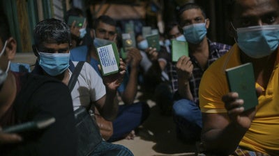 Migrant workers show their passport during a raid in Dengkil, outside Kuala Lumpur, Malaysia on June 21, 2021.