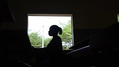 A young woman stands by a window at a secondary school in Dakar. 