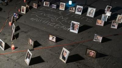 Framed photos placed on the ground around chalk writing that says "Black trans lives matter #allthetime"