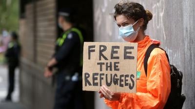 A protester holds a sign calling for the release of refugees being detained inside the Park Hotel in Melbourne, Australia