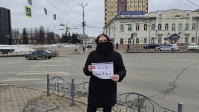 A woman holds a sign while standing at a street corner in Russia