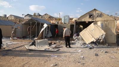 People assess the damage caused by a cluster munition attack of the Maram camp in Syria.