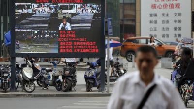 Pedestrians walk across a crossroad as a big electronic screen supported by face-recognition system shows the image of a jaywalker at the intersection in Nanjing city, east China's Jiangsu province, July 4, 2019. 