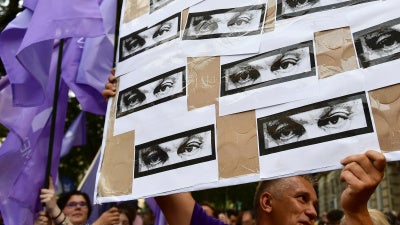 A man holds a banner showing the eyes of Hungarian Prime Minister Viktor Orban during a protest