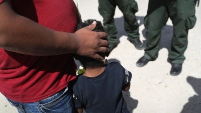 A father embraces his son in front of border agents