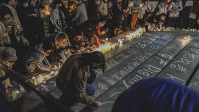 A protester writes "dignity" in English and Chinese in a show of solidarity with the White Paper protest in China at the University of Washington in Seattle, December 4, 2022.