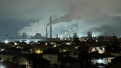 Smoke billowing from towers at a coal plant near a residential neighborhood