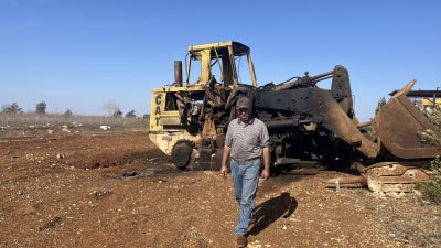 Ibrahim Karim, standing in front of one of the damaged bulldozers from Israeli strikes on August 6, 2025 on Deir Seryan, southern Lebanon.