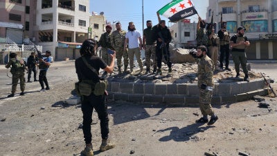 Syria's security forces pose for a picture on a roundabout in the predominantly Druze city of Sweida on July 15, 2025, following clashes between Bedouin communities and Druze fighters. Syrian government forces entered the majority Druze city of Sweida on July 15, 2025, the interior ministry said, aiming to end clashes with Bedouin communities  that have killed nearly 100 people.