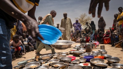 Sudanese refugees from Zamzam camp outside of El Fasher, in Darfur, receive food at an Emergency Response Room Communal Kitchen while being relocated to the Iridimi transit camp in Tine, eastern Chad, May 4, 2025. 