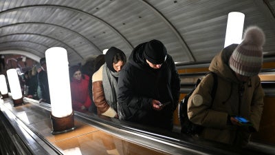 People use their smartphones while riding an escalator in the Moscow metro, Russia, on February 12, 2026.