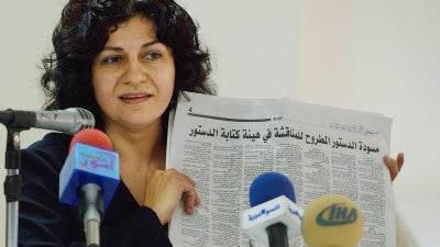 Yanar Mohammed, founder of the Women's Freedom Organization in Iraq, speaks to reporters while holding a newspaper copy of Iraq's new constitution,  Baghdad, July 28, 2005. 
