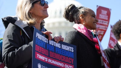 People hold signs at a rally and press conference against the SAVE America Act at the US Capitol in Washington, DC, on March 18, 2026.