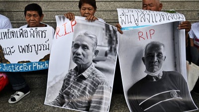 People hold photos and placards outside of a courthouse