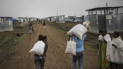 Internally displaced people carry food parcels during a distribution at Seba Care displaced persons camp in Mekelle, Tigray region, Ethiopia, July 19, 2024.