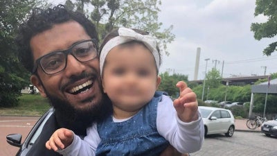 A picture of Omar smiling holding his daughter Amal