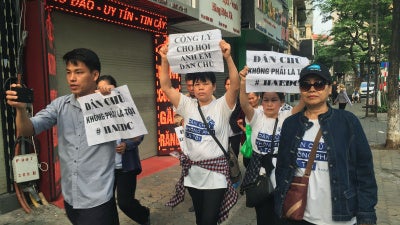  Protesters, including Can Thi Theu and Trinh Ba Tu, display placards as they march towards a courthouse during the trial of the prominent lawyer Nguyen Van Dai and five other activists in Hanoi, Vietnam, on April 5, 2018.