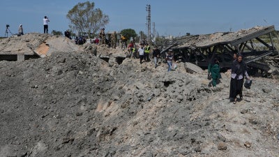 People cross on foot through a crater following an Israeli airstrike that destroyed the Qasmieh Bridge near the coastal city of Tyre, south Lebanon, April 16, 2026.