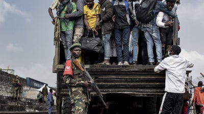 Un combattant du M23 monte la garde pendant que des personnes montent à bord d’un camion lors du recrutement de civils, de policiers, et d’anciens soldats de l’armée congolaise à Goma, en République démocratique du Congo, le 23 février 2025. 