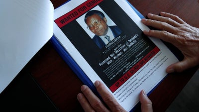 The head of the Gendarmerie’s Central Office for Combating Crimes Against Humanity, Genocides and War Crimes (OCLCH), displays documents with a wanted poster of Félicien Kabuga, May 19, 2020.