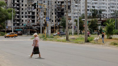 Une femme marchait dans une rue de Severodonetsk, ville occupée par les forces russes dans la région de Louhansk dans l'est de l'Ukraine, le 8 août 2024 ; à l’arrière-plan, les dommages subis par l’immeuble résidentiel de gauche lors des frappes russes étaient encore visibles.
