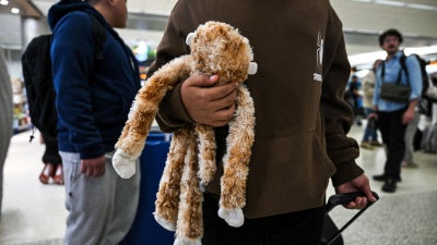 A child from Guatemala holds his stuffed monkey as he waits inside Miami International Airport to leave the United States and reunite with his recently deported parents in Guatemala, in Miami, Florida, December 4, 2025.