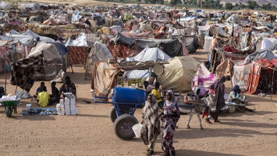 Displaced Sudanese people who fled El-Fasher after the city fell to the Rapid Support Forces (RSF), walk in the Um Yanqur camp, located on the southwestern edge of Tawila, in western Darfur, on November 3, 2025.