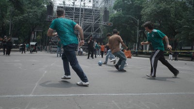 Passersby take part in a pickup football game organized by civilian search collectives on Mexico City's Paseo de la Reforma during the World Cup, July 2026. 
