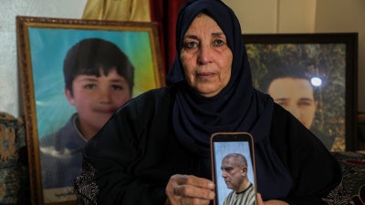 Samira Hahami stands in front of photos of her son, Hamza Ali al-Khatib, who at the age of 13 in May 2011, died in security forces custody. His body bore apparent signs of torture.