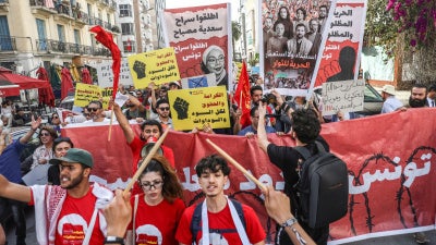 Tunisians hold up placards during a march organized by the Campaign Against the Criminalization of Civil Work to protest racism in Tunis, April 11, 2026