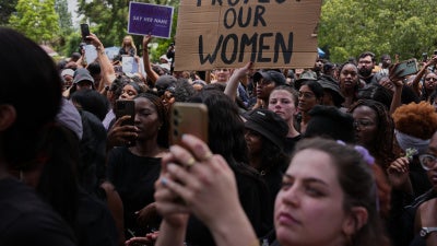 Participants hold signs during a gender-based violence protest at the forecourt of the botanical gardens in Johannesburg, South Africa, November 21, 2025.
