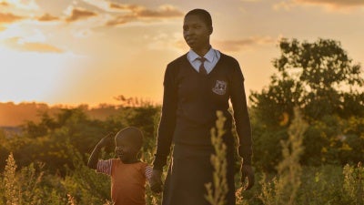 “Angela,” 20, walks with her son near her home after returning from school in Migori county, western Kenya