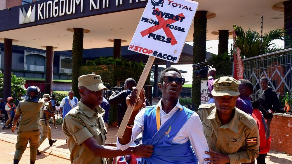 security officials detain a protester holding a placard
