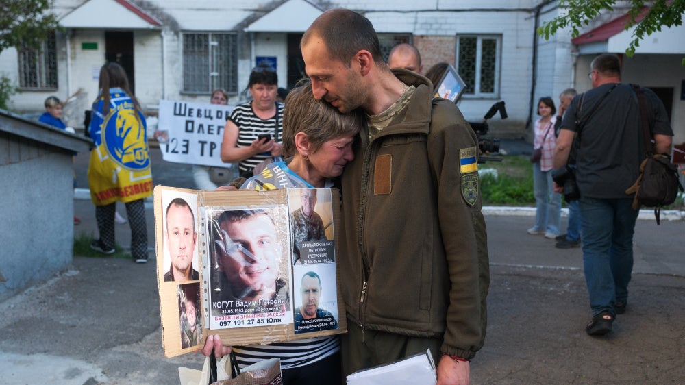 A Ukrainian serviceman released from Russian captivity during a prisoner exchange hugs a crying woman searching for her missing loved ones in Chernihiv Oblast, Ukraine, on May 23, 2025.