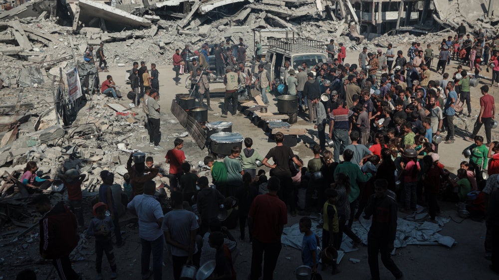 Palestinians flock to the area where a charitable organization distributes hot food as food crisis persists in Beit Lahia, Gaza on October 28, 2025. 